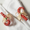 Two handcrafted candy cane napkin rings on a white cloth background