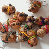A group of small handwoven capybaras, decorated with colorful beanies and scarves in pink, green, orange, purple, and yellow.