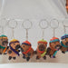 A group of small handwoven capybaras, decorated with colorful beanies and scarves in pink, green, orange, purple, and yellow.