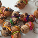 A group of small handwoven capybaras, decorated with colorful beanies and scarves in pink, green, orange, purple, and yellow.