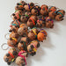 A group of small handwoven capybaras, decorated with colorful beanies and scarves in pink, green, orange, purple, and yellow.