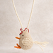 Handmade straw chicken ornament hanging on a string against a neutral background